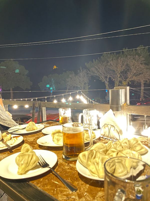 Khinkali dumplings and beer on a terrace overlooking illuminated Jvari